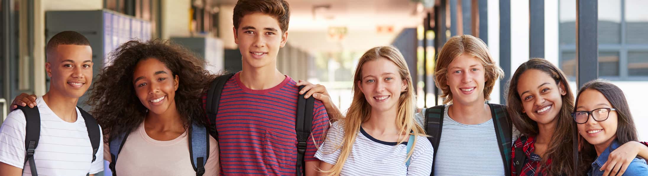 Smiling students standing together in a school hallway